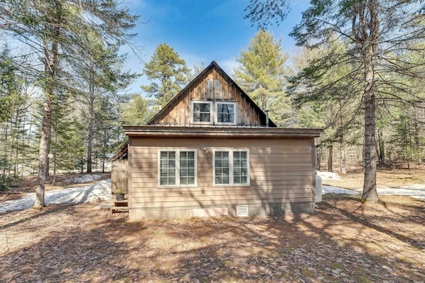 Situated in a forested area, this cabin offers a simple, rustic retreat with a pitched roof and a cozy porch.