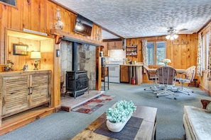 Cozy cabin-style accommodation with a stone fireplace, wood-burning stove, and kitchen area.