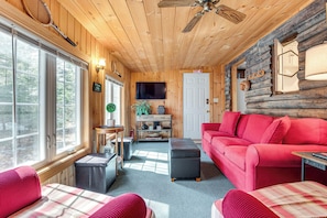 Cozy cabin-style room with a large window, comfortable sofa, and television.