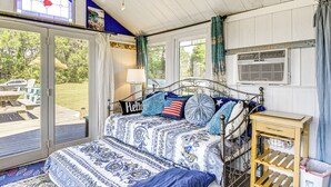 A bedroom with a bed, a nightstand, a window, and a view of the outdoors. - Tiny House w/ Big Views: Cabin in Shiloh! (Shiloh)