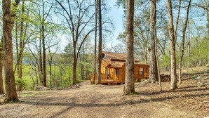 Uma cabana numa área arborizada com uma trilha de terra que leva até ela.