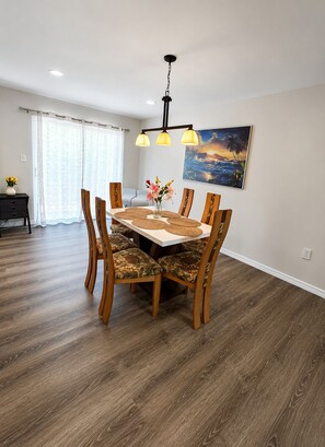 A dining area with a wooden table, chairs, and a painting on the wall. - 3-bedroom house in charming Gulfport close to beach with WiFi, AC. Book now (Gulfport)