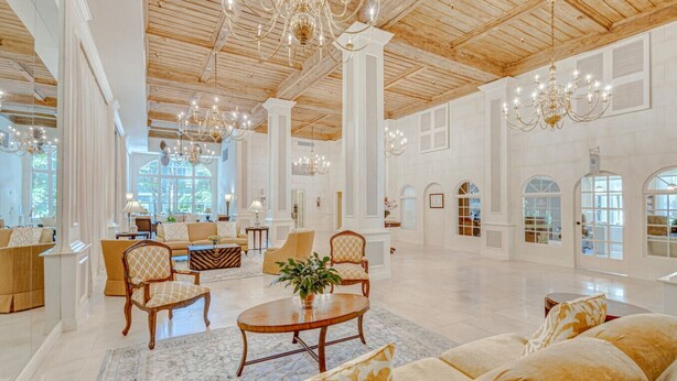 A spacious lobby with high ceilings, chandeliers, and a mix of seating arrangements including sofas and armchairs.