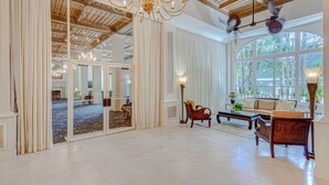A spacious room with a high ceiling, large windows, and a chandelier.