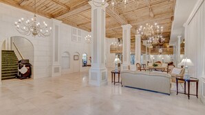 A spacious lobby with high ceilings, chandeliers, and a grand staircase.