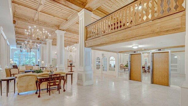 A spacious lobby with high ceilings, chandeliers, and a wooden balcony. - Palm Beach Regency Walk to Beach (Palm Beach)