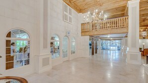 A spacious hotel lobby with high ceilings, arched windows, and a wooden balcony. - Palm Beach Regency Walk to Beach (Palm Beach)