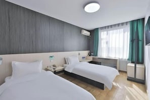 A hotel room with two beds, a bedside table with a lamp, a window with curtains, and a ceiling light. - Wenna Hotel (Changchun Qianjin Street Qianwei Hospital) (Changchun)