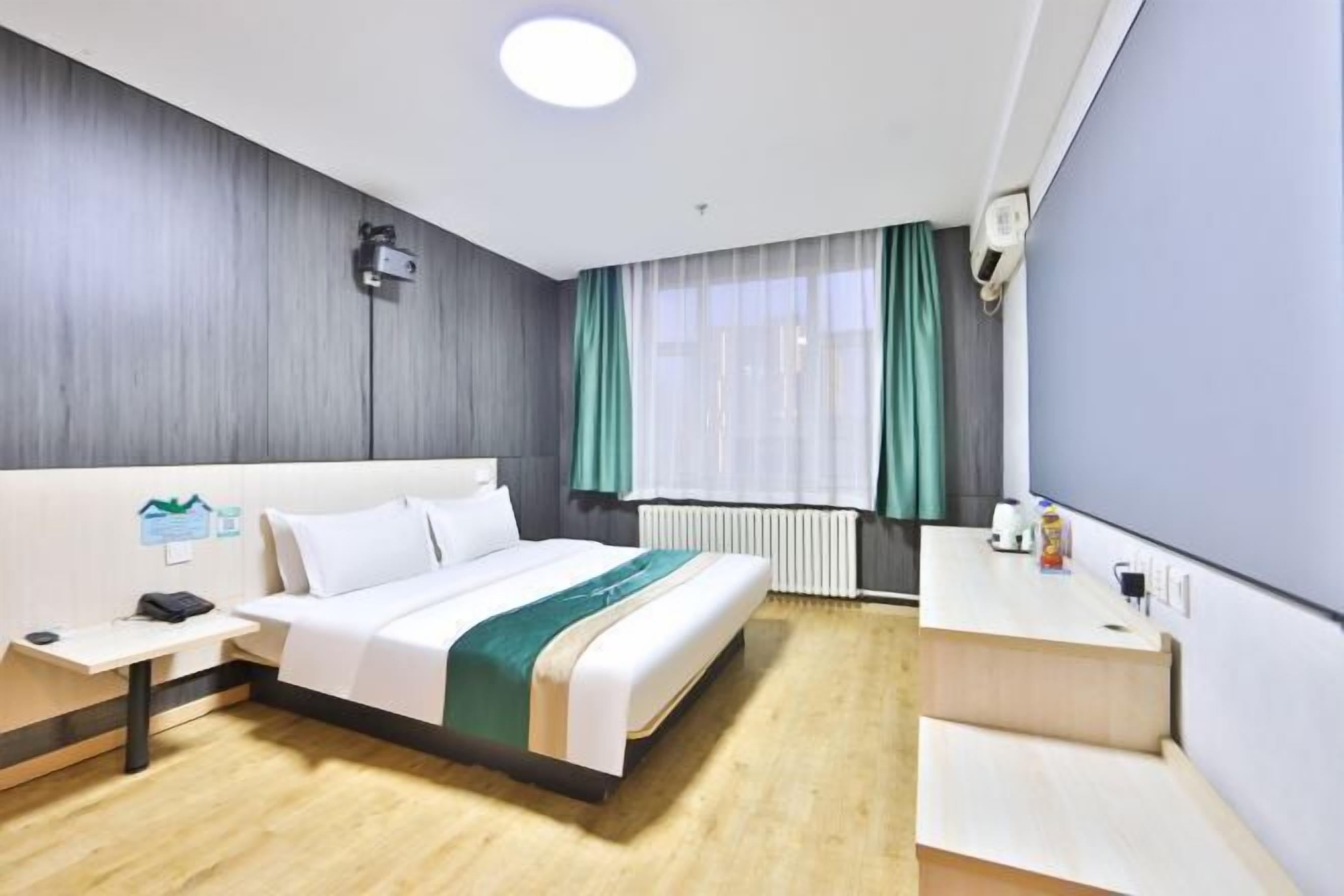A hotel room with a bed, bedside table, and a desk.