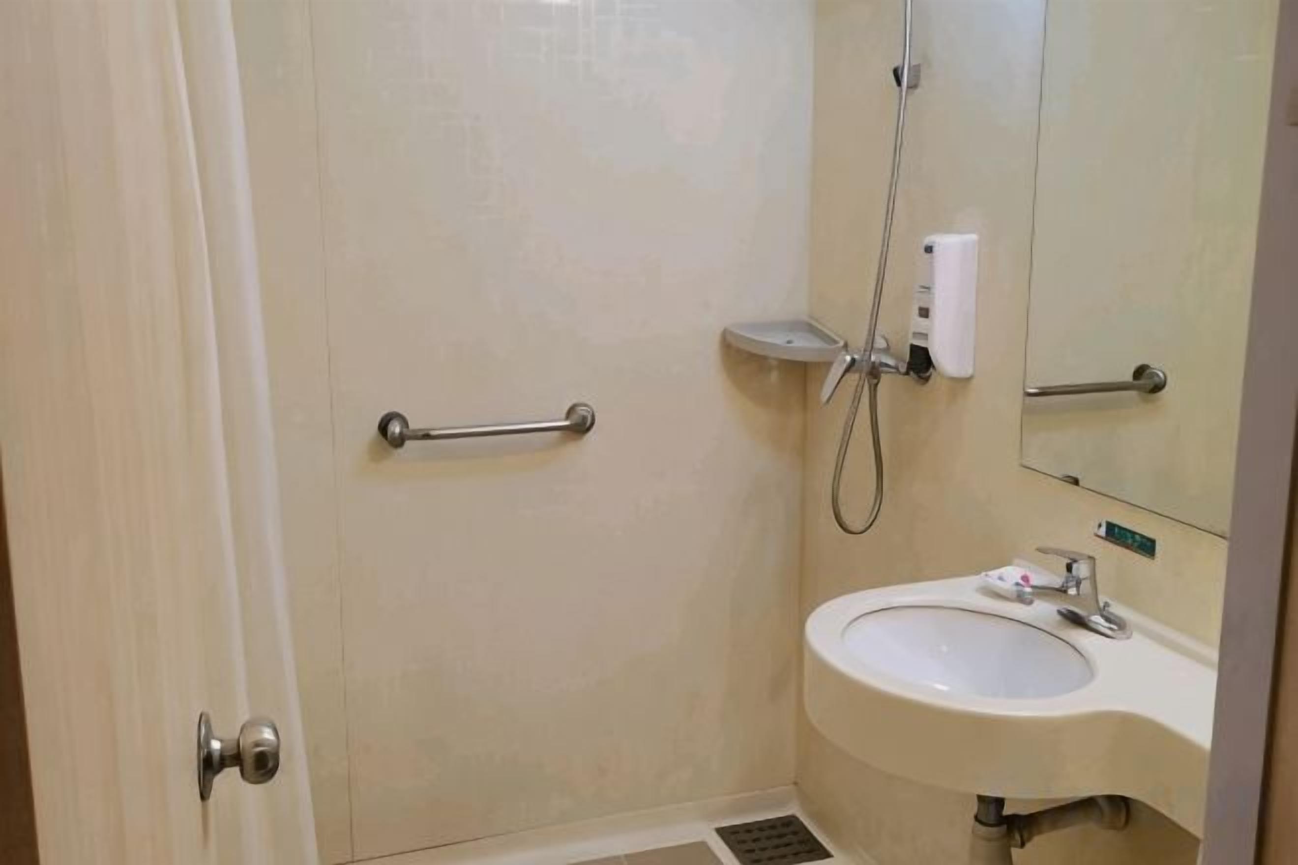 A bathroom with a shower, a sink, and a mirror.