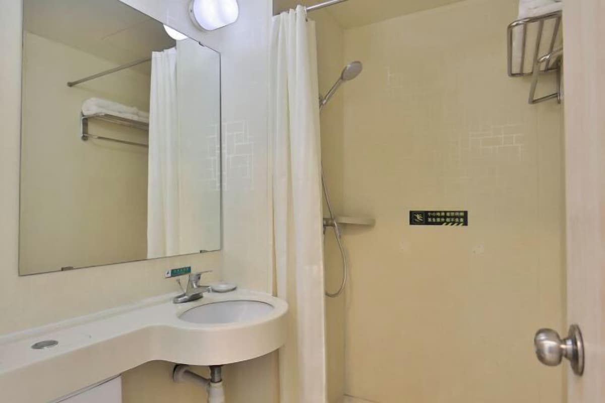 A bathroom with a sink, mirror, and shower.