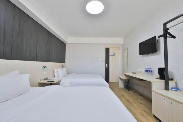 Habitación de hotel con dos camas, un escritorio, un televisor y un espejo.