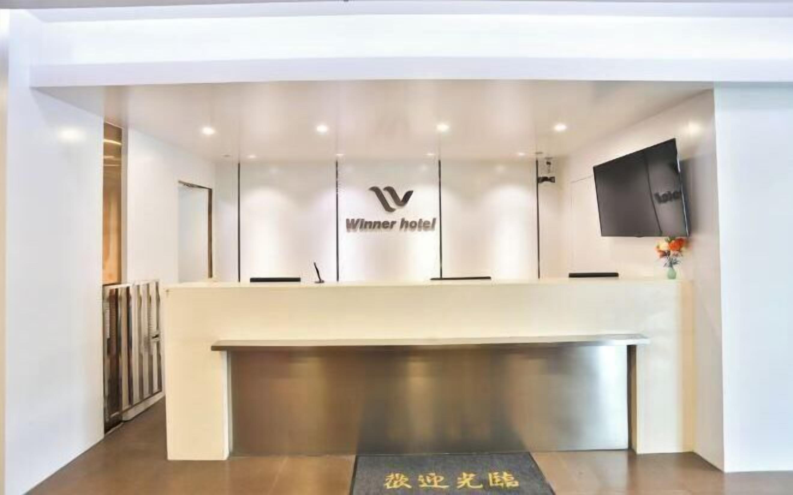 Un mostrador de recepción de hotel con diseño moderno, un logotipo y un televisor de pantalla plana.