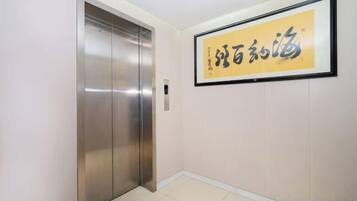 An elevator in a hallway with a framed sign on the wall.