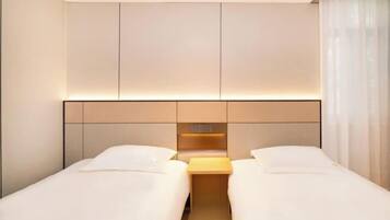 A hotel room with two beds, a wooden headboard, and a nightstand.