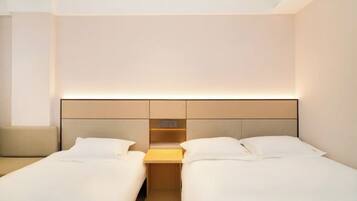 A hotel room with two beds, a nightstand, and a built-in shelf.