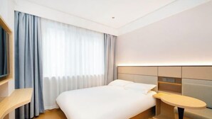 Une chambre d’hôtel moderne, équipée d’un lit, d’une table de chevet et d’une petite table ronde.