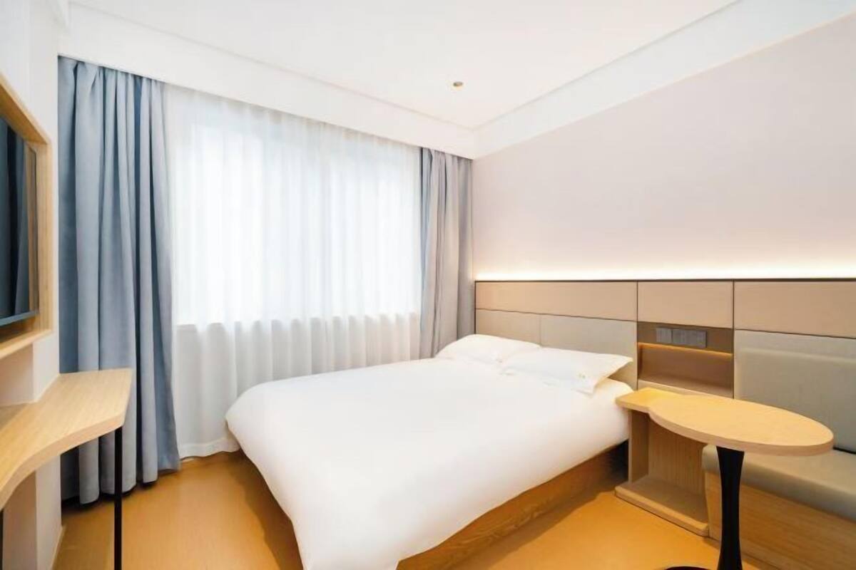Une chambre d’hôtel moderne, équipée d’un lit, d’une table de chevet et d’une petite table ronde.