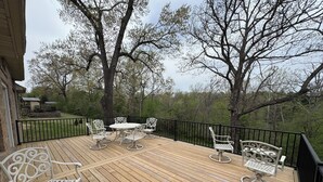 A wooden deck with outdoor furniture, including a table and chairs, surrounded by a black railing.