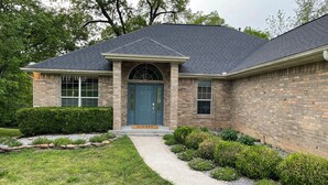 A two-story house with a dark roof, a brick facade, and a front entrance with a blue door.