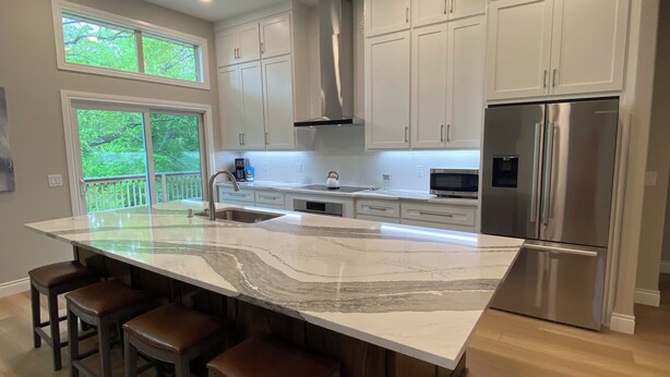 A modern kitchen with a large island, stainless steel appliances, and white cabinetry.