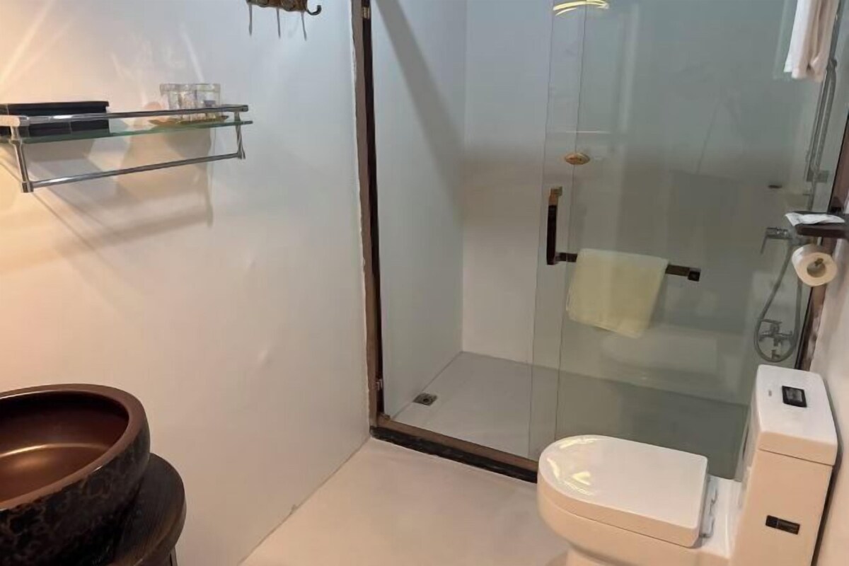 Een moderne badkamer met een douchecabine van glas, een wit toilet en een marmeren wastafel.