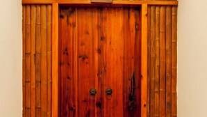 A wooden door with two brass handles and a vertical bamboo panel on either side.
