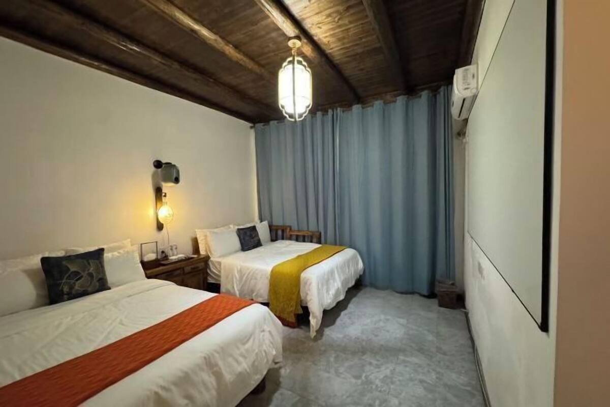 Een hotelkamer met twee bedden, een nachtkastje, een lamp en een plafondventilator.