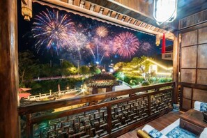 A room with a large window overlooking a traditional Chinese garden and a pagoda, with a view of fireworks in the distance. - Yangshuo Fushan Hai Cuiying Huating Homestay (Yulong River Eternal Love) (Yangshuo)