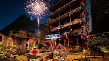 Un edificio tradicional con un balcón, rodeado de mesas y sillas al aire libre y un comedor.