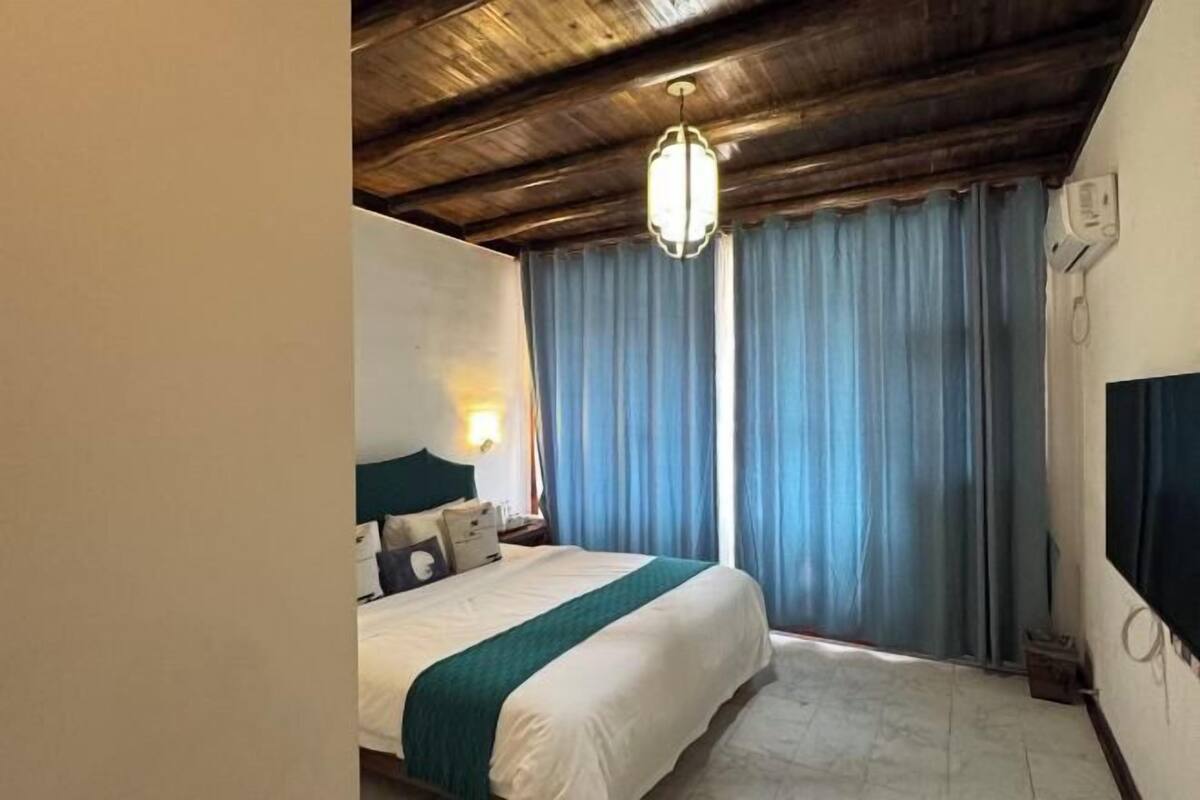 Een hotelkamer met een bed, nachtkastje, tv aan de muur en plafondventilator.