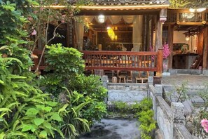 A traditional building with a wooden balcony, a stone pathway, and a small water feature. - Yangshuo Fushan Hai Cuiying Huating Homestay (Yulong River Eternal Love) (Yangshuo)