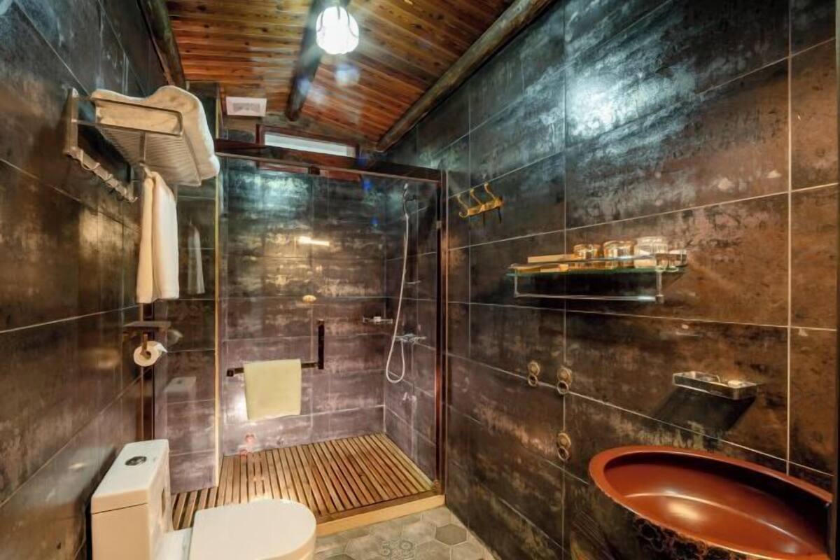 Een moderne badkamer met een douchecabine van glas, een houten vloer en een wastafel in vintage-stijl.