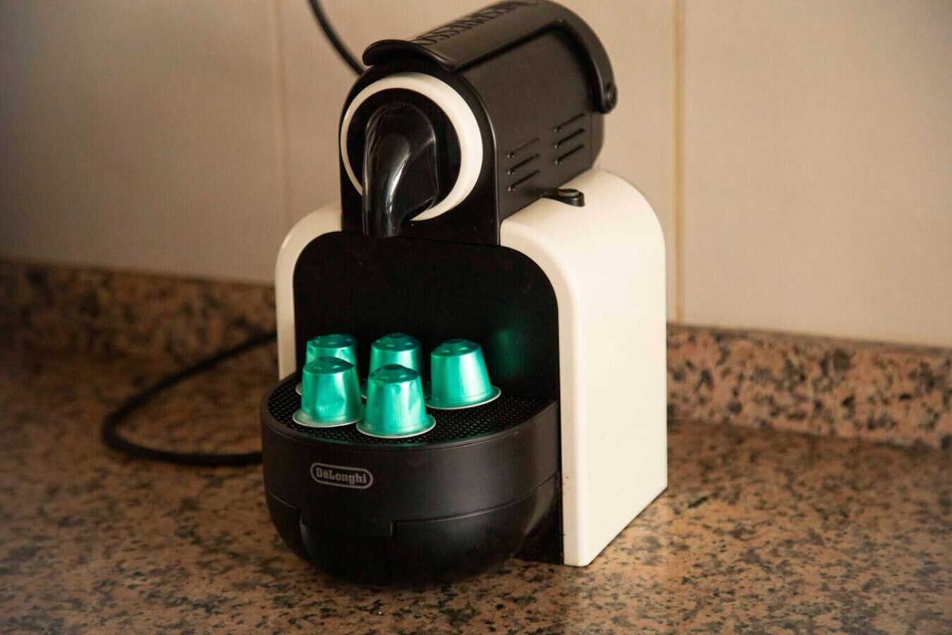 A black and white coffee machine with a single outlet and a power cord.