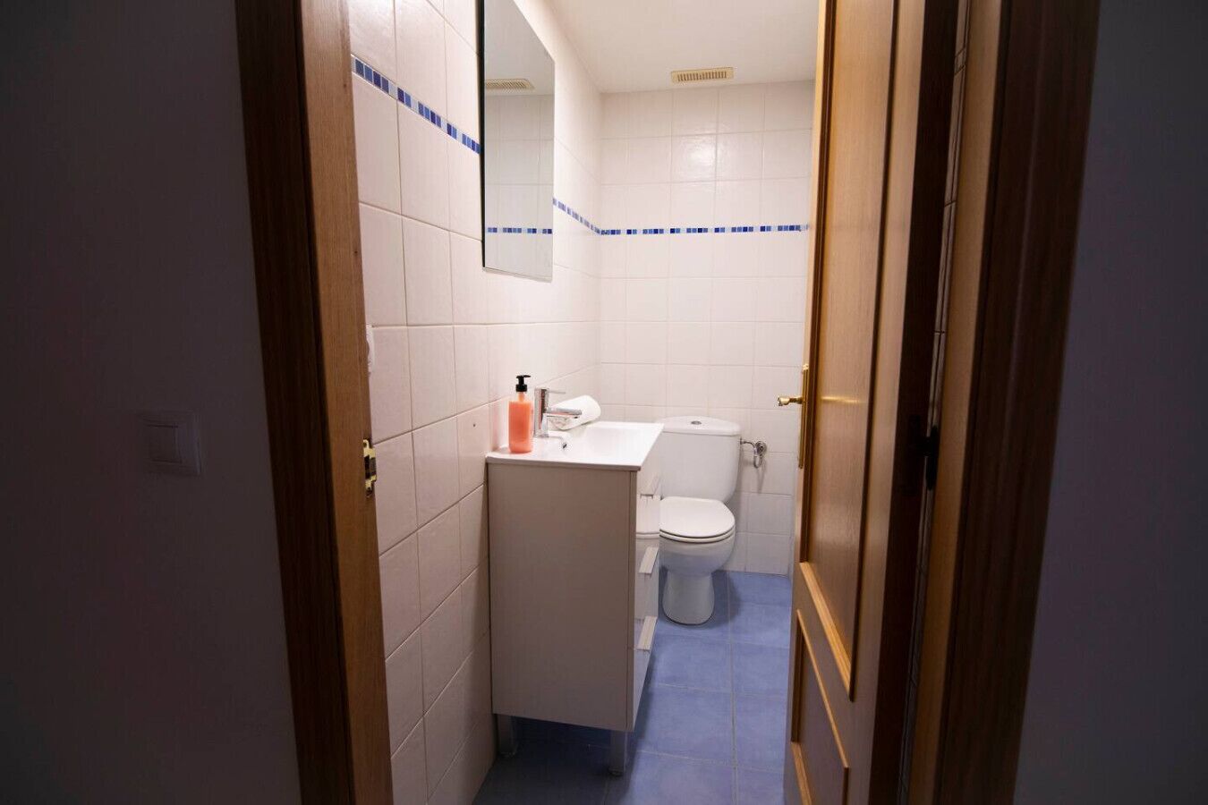 A small bathroom with a toilet, sink, and mirror.