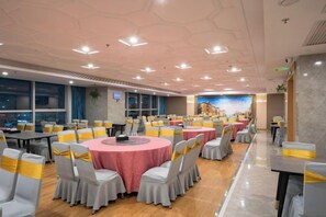 Une salle de conférence avec des tables rondes, des chaises et une grande fenêtre.