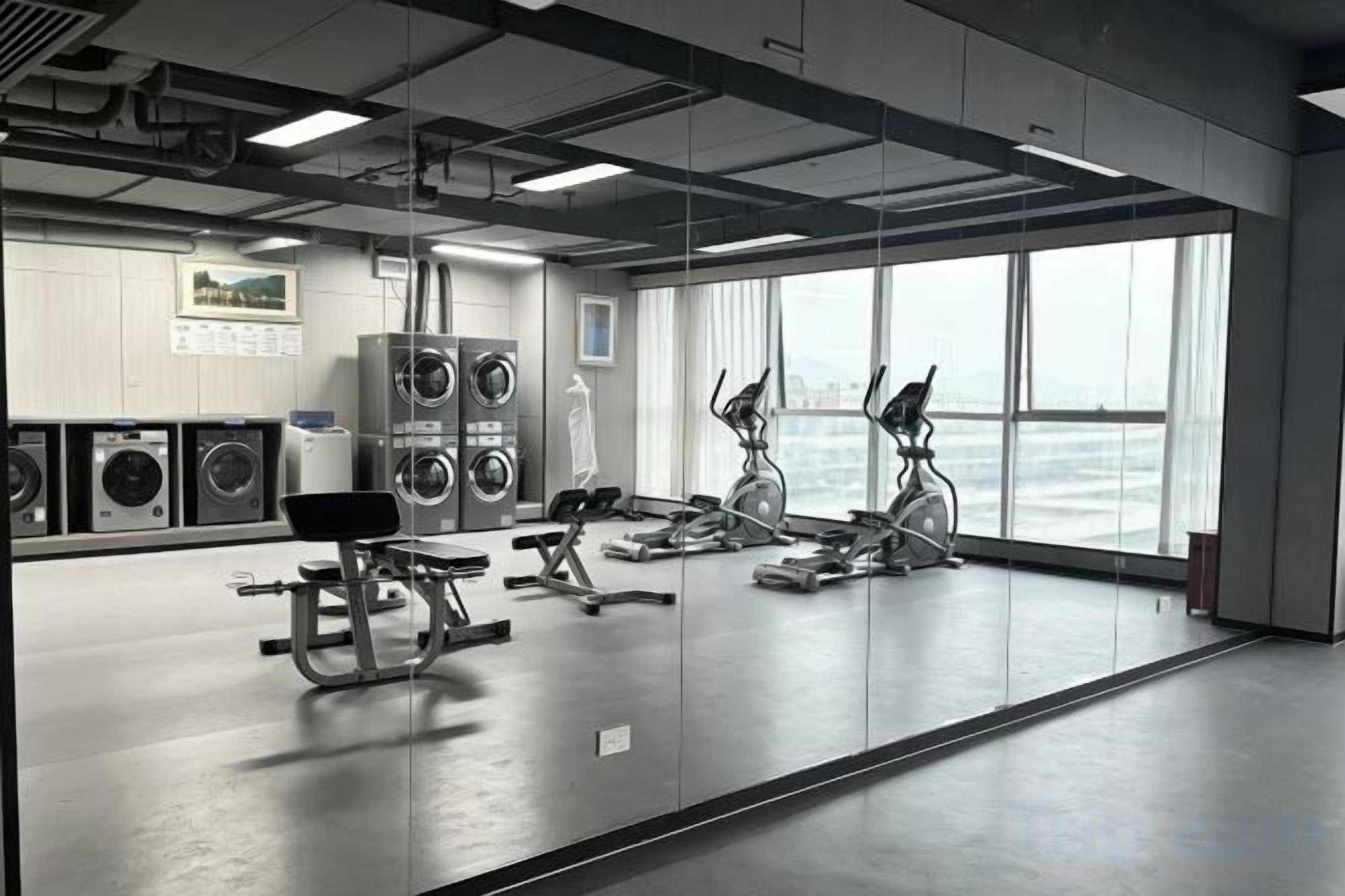 Une salle de sport équipée de matériel d’exercice, dotée de grandes fenêtres et offrant une vue sur la mer.