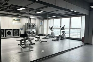 A gym with exercise equipment, large windows, and a view of the sea. - Hangzhou Yuecheng Audio & Video International Hotel (Boao Xinhan Road Subway Station) (Hangzhou)