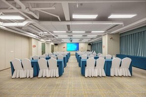A conference room with rows of tables and chairs, a large screen at the front, and a blue accent wall. - Hangzhou Yuecheng Audio & Video International Hotel (Boao Xinhan Road Subway Station) (Hangzhou)