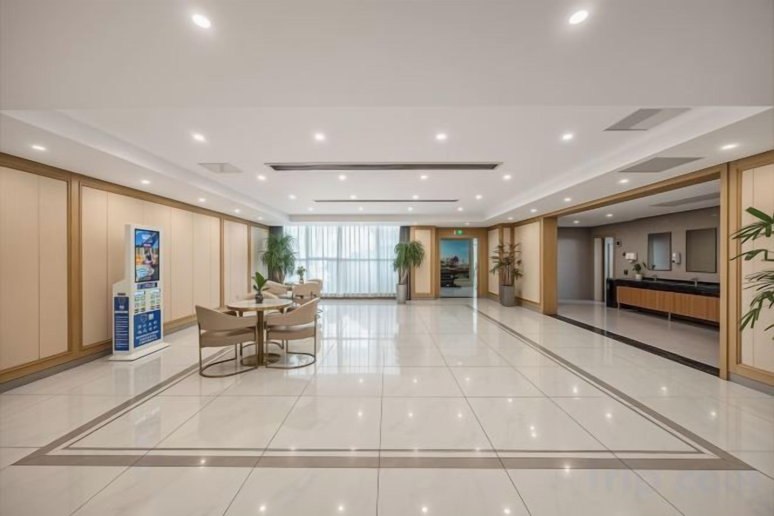 A hotel lobby with a reception desk, a seating area, and a large window.