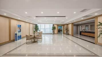 A hotel lobby with a reception desk, a seating area, and a large window.