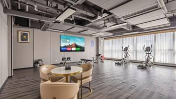 A modern conference room with a large flat-screen TV, ergonomic chairs, and a wooden floor.