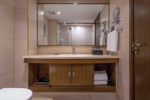 Ein Badezimmer mit einem Holzwaschtisch, einem großen Spiegel, einem Waschbecken und einer Toilette.