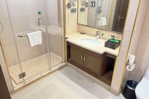 Ein modernes Badezimmer mit Duschkabine aus Glas, einem Waschbecken mit Ablagefläche und einem großen Spiegel.