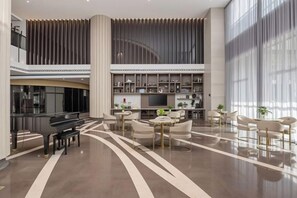 A spacious lobby with a piano, seating area, and a large window. - Hangzhou Yuecheng Audio & Video International Hotel (Boao Xinhan Road Subway Station) (Hangzhou)