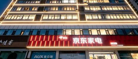 A multi-story hotel with illuminated signage, a visible entrance, and a clear view of the surrounding urban environment.