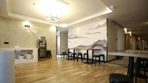 A modern interior with wooden flooring, a reception desk, bar area, and mountain-themed wall art. - Qingmu Hotel (Nanjing Xinzhuang Metro Station) (Nanjing)
