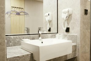 A modern bathroom with a white sink, a mirror, and a hairdryer mounted on the wall. - Qingmu Hotel (Nanjing Xinzhuang Metro Station) (Nanjing)