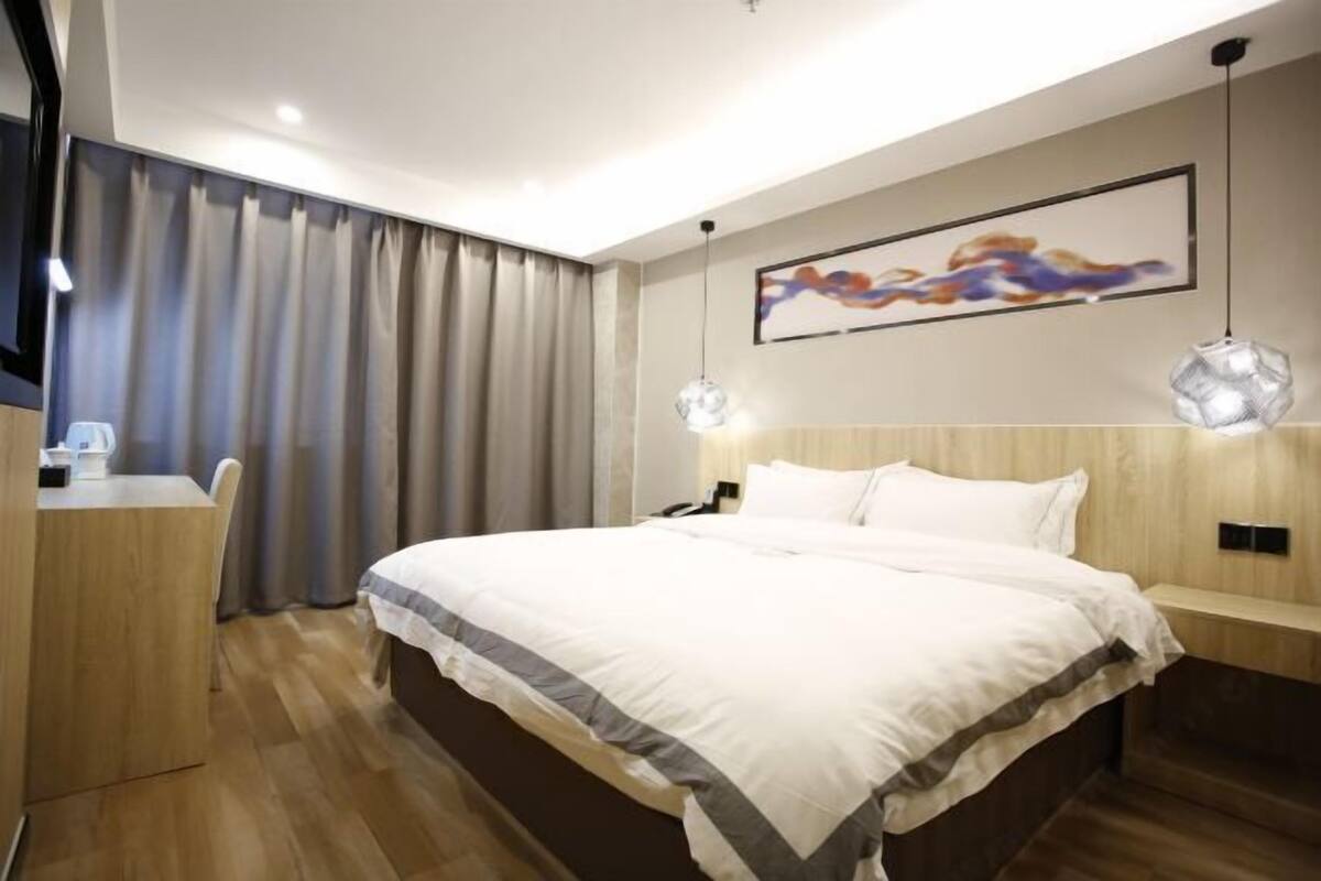 A modern hotel room with a large bed, a desk, and a chair.