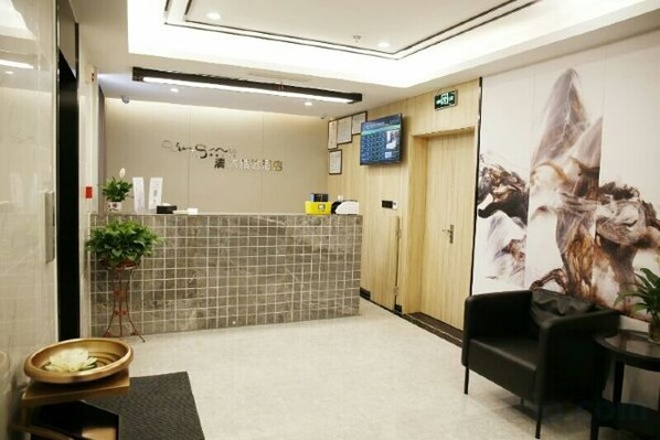 A reception area with a tiled counter, a television, a plant, and a large poster on the wall.